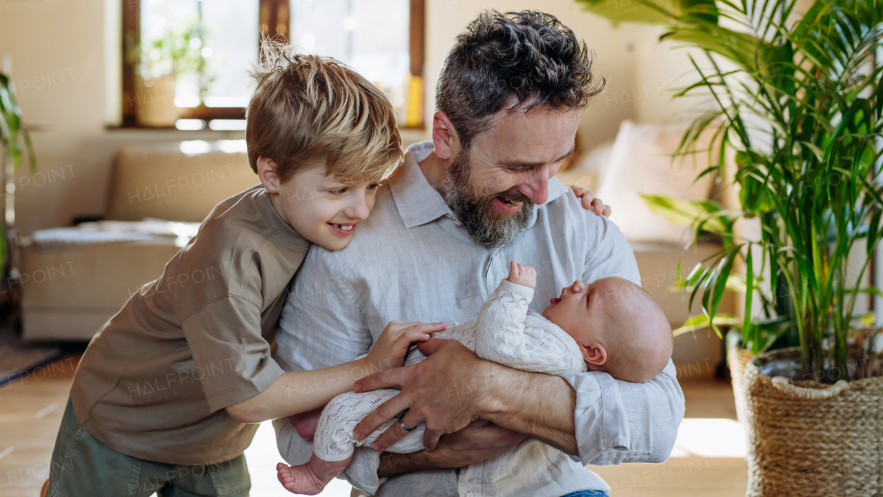 Father and boy holding newborn baby. New sibling. Unconditional paternal love and Father's Day concept.