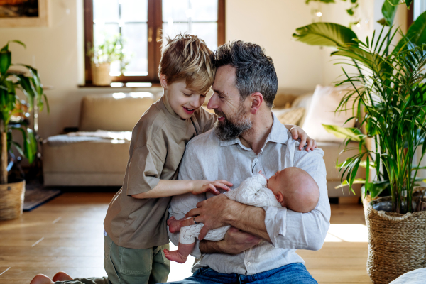 Father and boy holding newborn baby. New sibling. Unconditional paternal love and Father's Day concept.