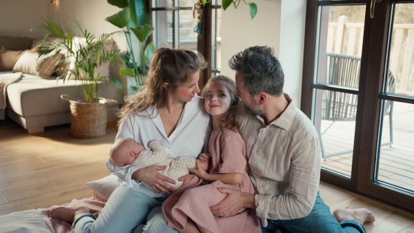 Mother breastfeeding newborn, big sister looking at new baby in mom's arms. Strong family, bonding, parents' unconditional love for their children.