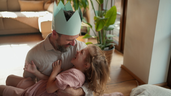 Father with daughter on floor laughing together, having fun and making faces. Girls dad. Unconditional paternal love, Father's Day concept.