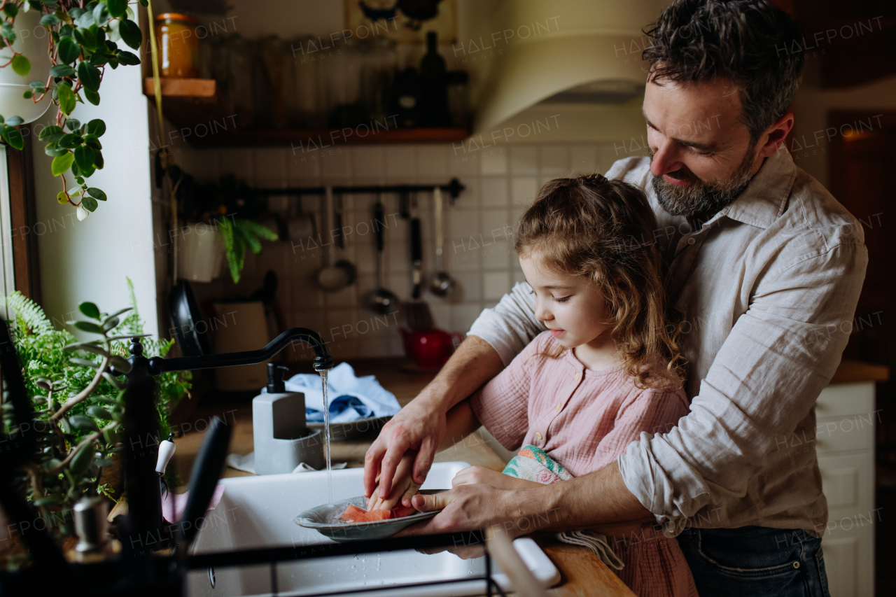 Dad and daughter cooking together in kitchen, cleaning fruit in sink. Girls dad. Unconditional paternal love and Father's Day concept.