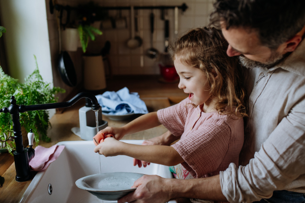 Dad and daughter cooking together in kitchen, cleaning fruit in sink. Girls dad. Unconditional paternal love and Father's Day concept.