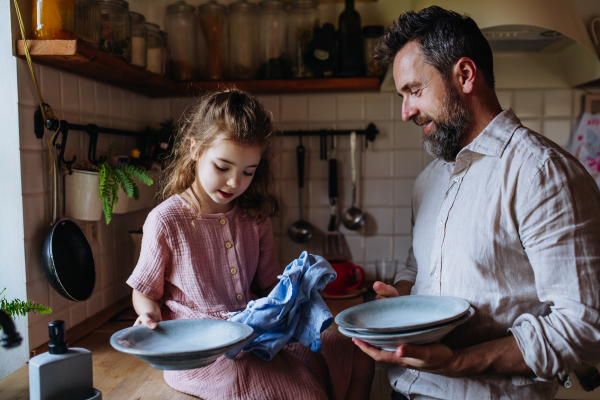 Dad and daughter cooking together in kitchen, cleaning fruit in sink. Girls dad. Unconditional paternal love and Father's Day concept.