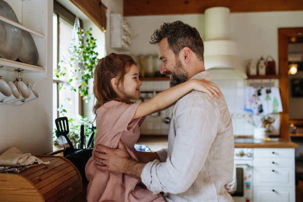 Daughter hugging father lovingly, sitting on kitchen counter. Unconditional paternal love and Father's Day concept.