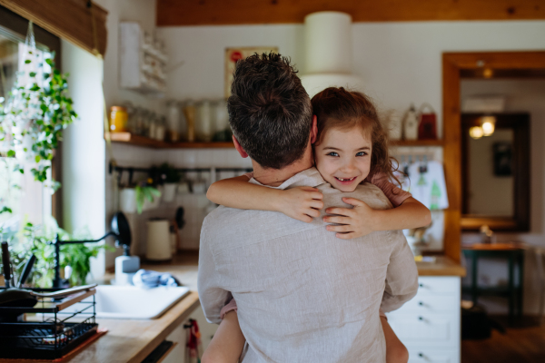 Daughter hugging father lovingly, looking at camera, smiling with gap toothed grin. Unconditional paternal love, Father's Day concept.