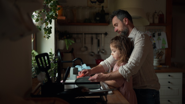 Dad and daughter cooking together in kitchen, cleaning fruit in sink. Girls dad. Unconditional paternal love and Father's Day concept.