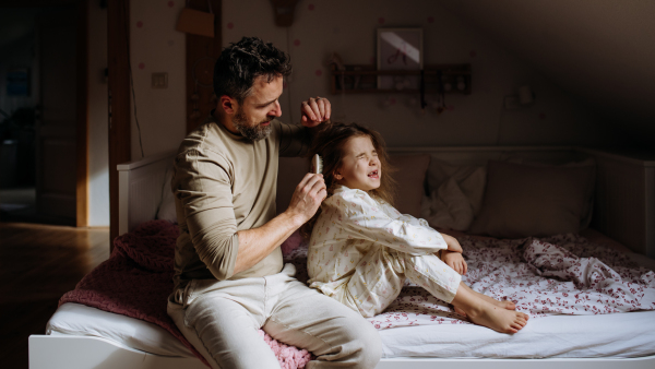 Father braiding his daughter's hair, combing hair as part of bedtime routine. Single dad taking care of his daughter's hairstyle.