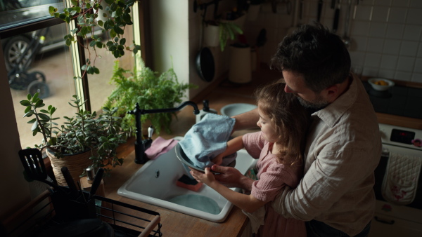 Dad and daughter cooking together in kitchen, cleaning fruit in sink. Girls dad. Unconditional paternal love and Father's Day concept.