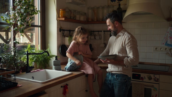 Dad and daughter cooking together in kitchen, cleaning fruit in sink. Girls dad. Unconditional paternal love and Father's Day concept.