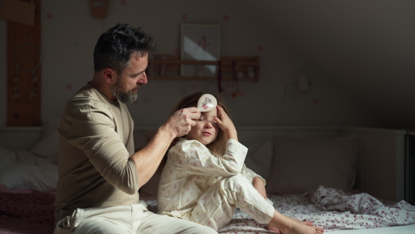 Father braiding his daughter's hair, combing hair as part of bedtime routine. Single dad taking care of his daughter's hairstyle.