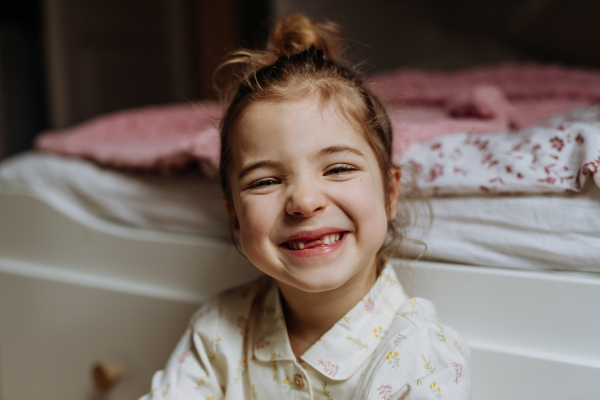 Portrait of cute girl smiling with a gap-toothed grin, missing her top front baby teeth.