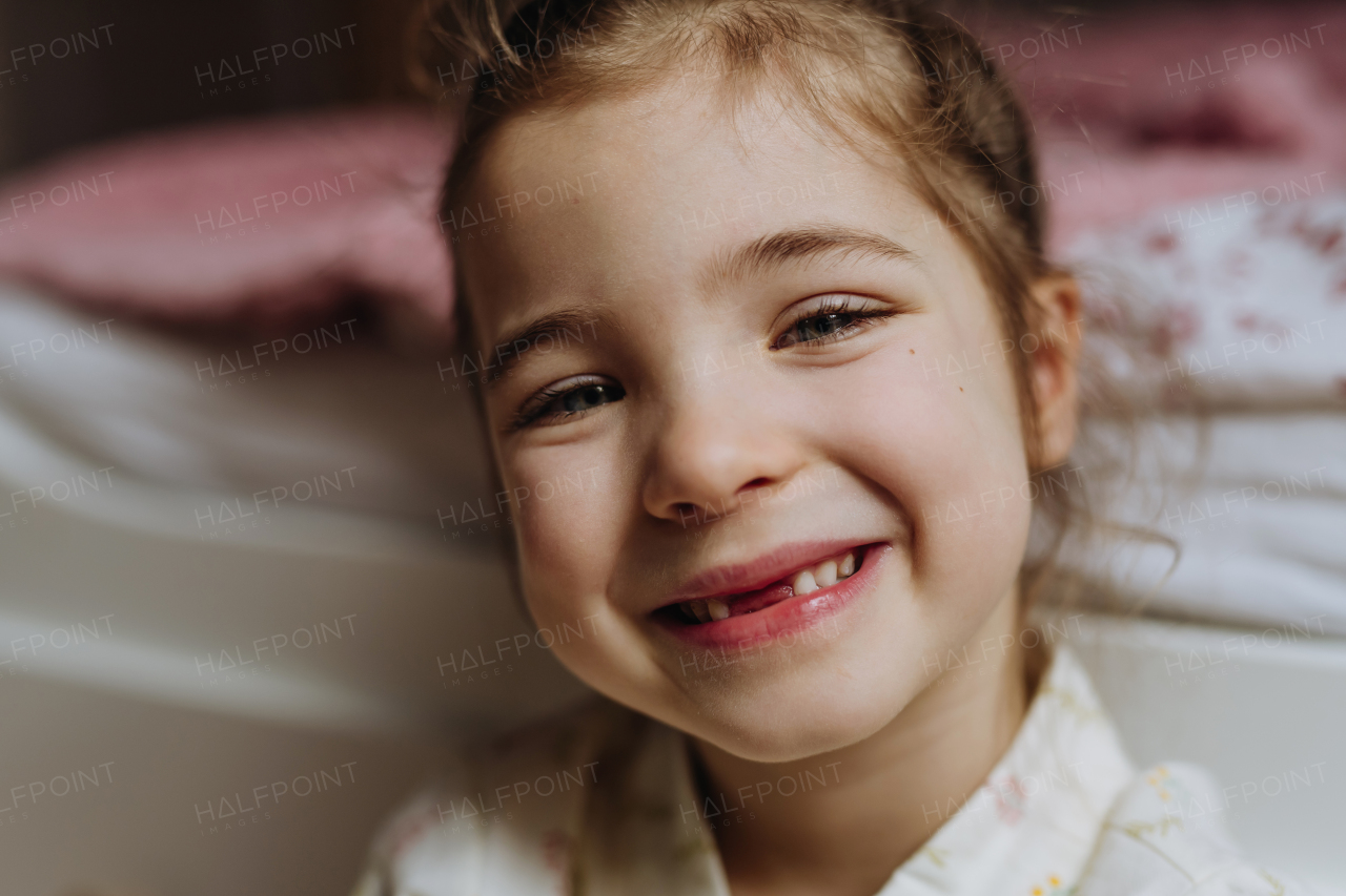 Portrait of cute girl smiling with a gap-toothed grin, missing her top front baby teeth.