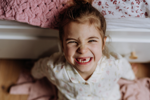 Portrait of cute girl smiling with a gap-toothed grin, missing her top front baby teeth.