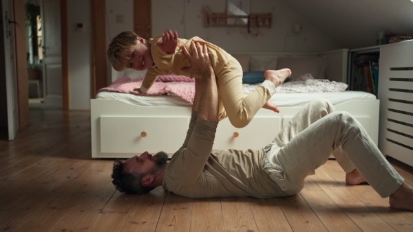 Father an son doing ariplane game, lifting boy up with hands like plane and aughing together. Boys dad. Unconditional paternal love, Father's Day concept.