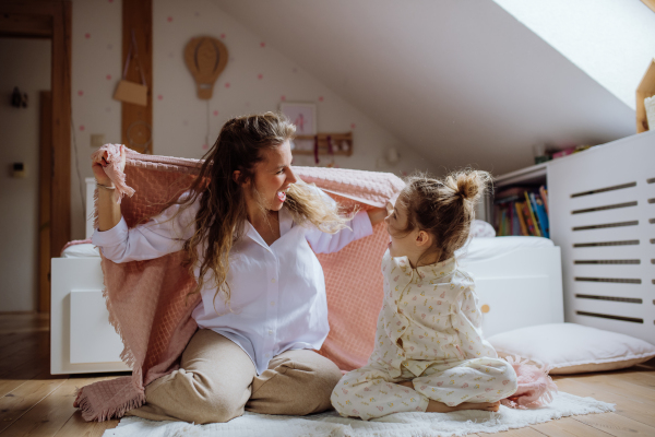 Mother and girl playing on floor, laughing together in kids room. Unconditional paternal love, Mother's Day concept. Girls mom