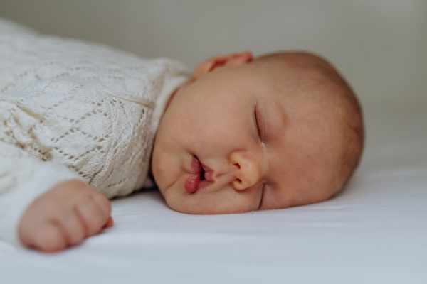 Portrait of cute little baby sleeping in bed, lying on on belly, closed eyes.