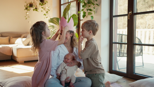 Mother after giving birth as a queen. Daughter giving mom a paper crown and admiration, love for mothers, concept of Mother's Day and women's strength.