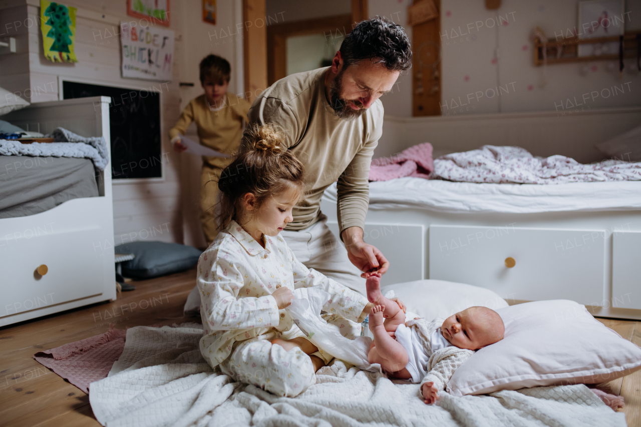 Girl helping her father change baby's diaper, new sibling. Unconditional paternal love and Father's Day concept.