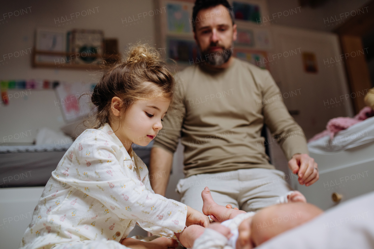 Girl helping her father change baby's diaper, new sibling. Unconditional paternal love and Father's Day concept.