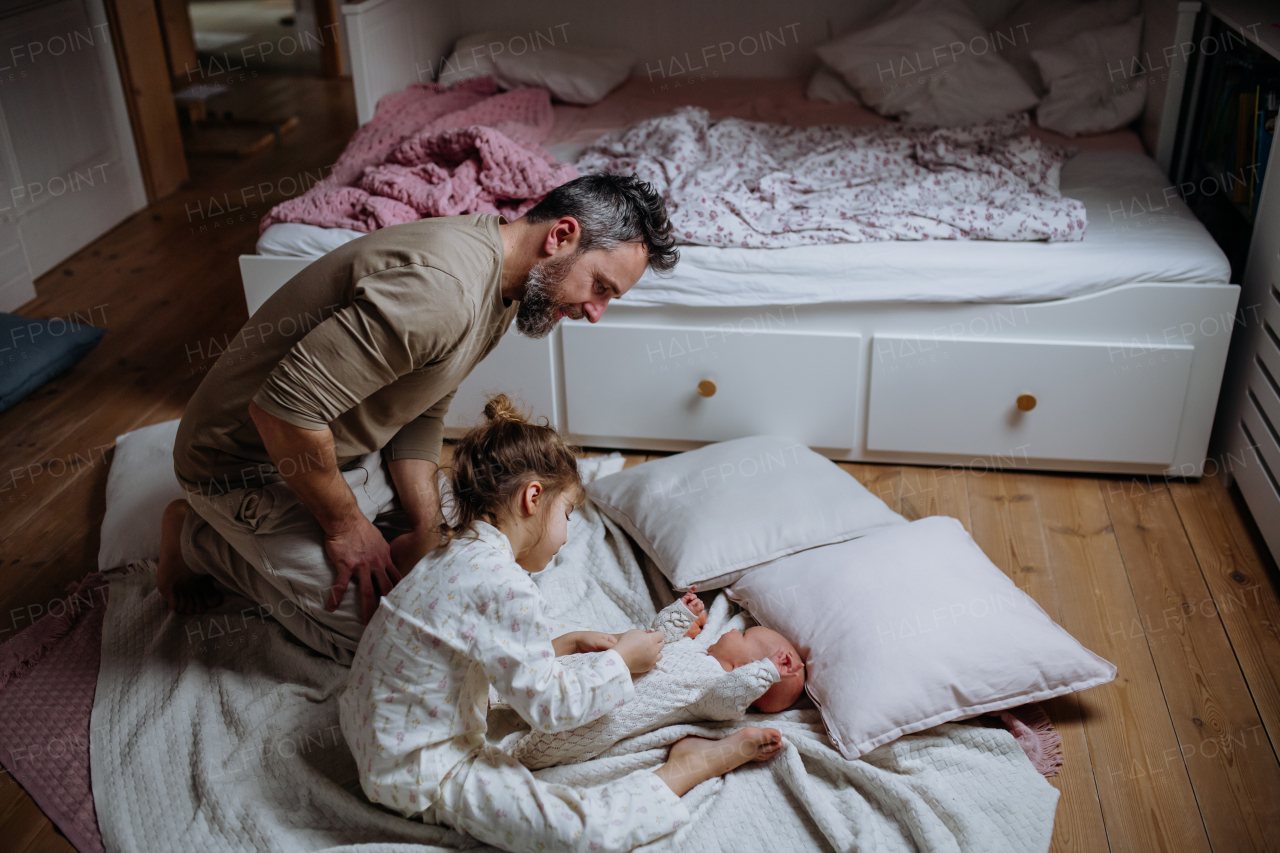 Girl helping her father change baby's diaper, new sibling. Unconditional paternal love and Father's Day concept.