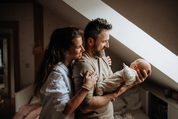 Parents holding newborn baby, looking at newborn lovingly. Unconditional paternal love, Father's Day and Mather's Day concept.