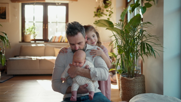 Father holding newborn baby girl, older daughter with them. New sibling. Girls dad. Unconditional paternal love and Father's Day concept.