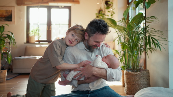 Father and boy holding newborn baby. New sibling. Unconditional paternal love and Father's Day concept.