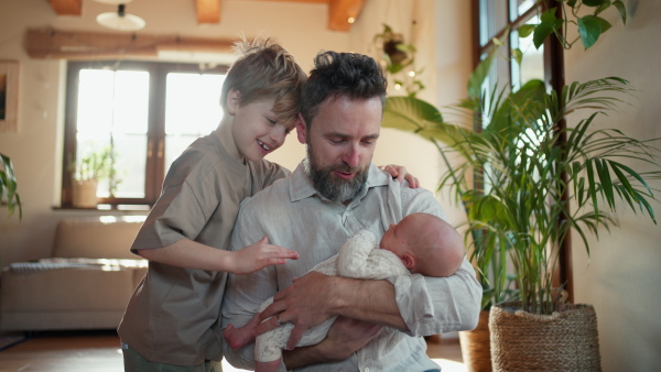 Father and boy holding newborn baby. New sibling. Unconditional paternal love and Father's Day concept.