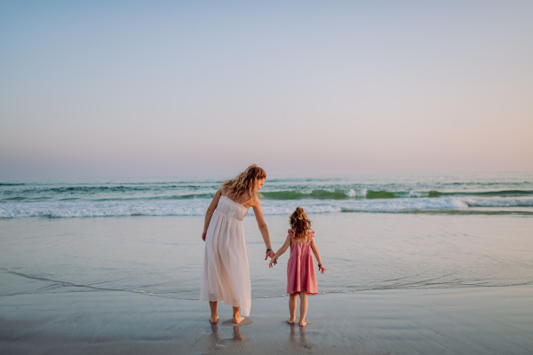 Mother with her little daughter enjoying time at the sea,rear view.