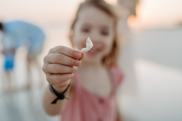 Cose-up of little girl holding sea shell, enjoying family holliday.