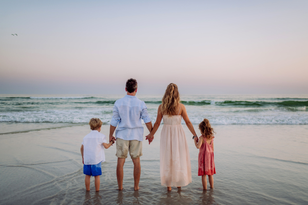 Happy family with little kids enjoying time at the sea in exotic country,rear view.