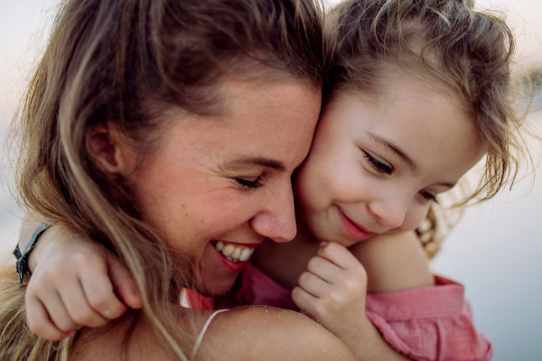 Portrait of mother and her little daughter, enjoying time at the sea.