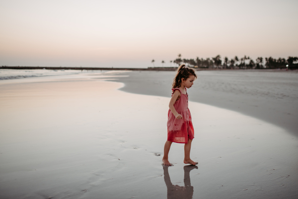 Little girl walking on the beach, enjoying summer exotic vacation.