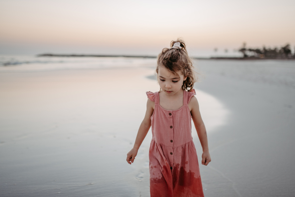 Little girl walking on the beach, enjoying summer exotic vacation.