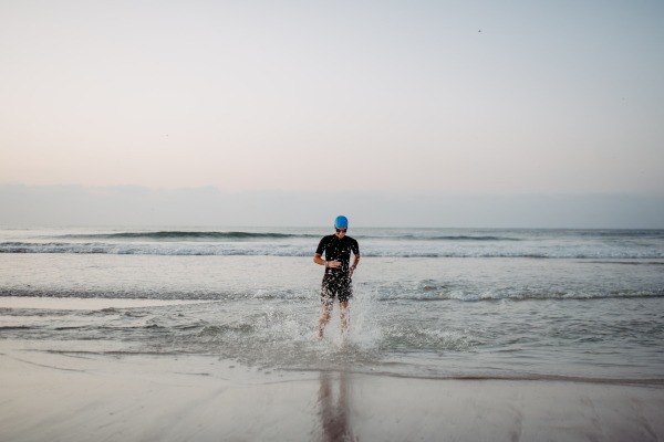 Woman in a neoprene running out of the ocean.