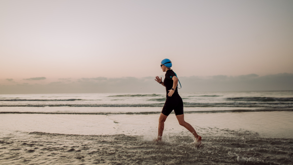 Woman in a neoprene running along of the ocean.