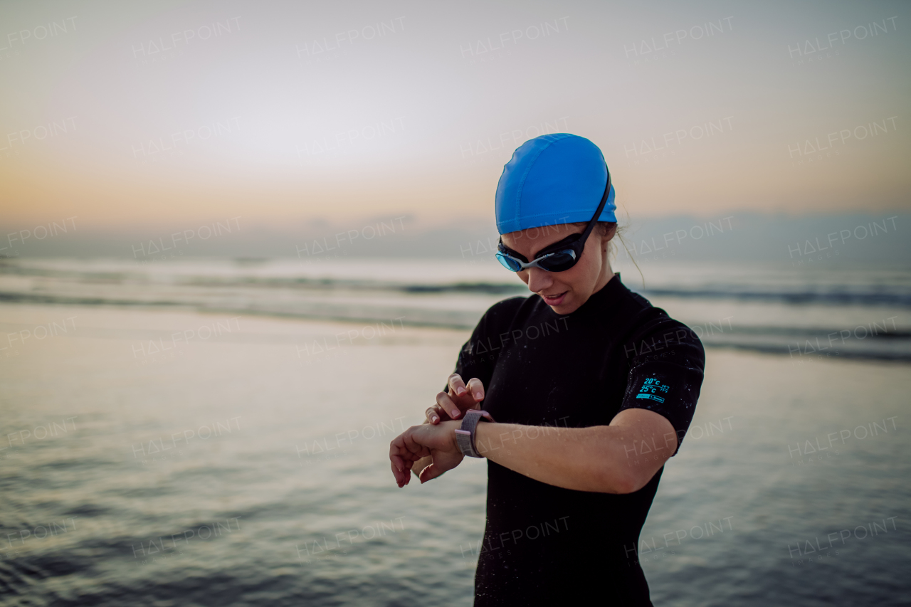 Woman in neoprene chcecking a smartwatch, after diving.