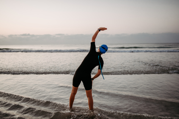 Young woman preparing for diving,stretching on the beach.