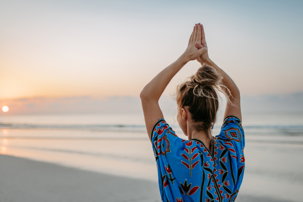 Rear view of young woman taking exercises at the beach, morning routine and healthy lifestyle concept.