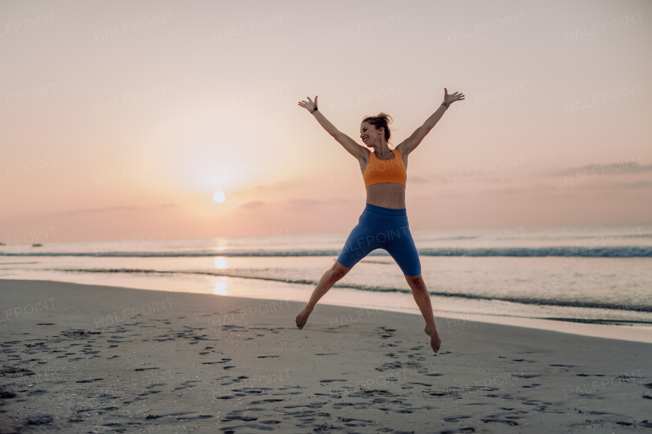 Young woman taking exercises at the beach, morning routine and healthy lifestyle concept.