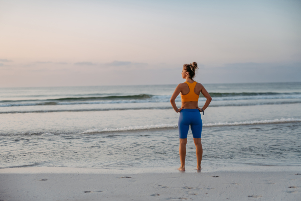 Rear view of young sportive woman at the beach.