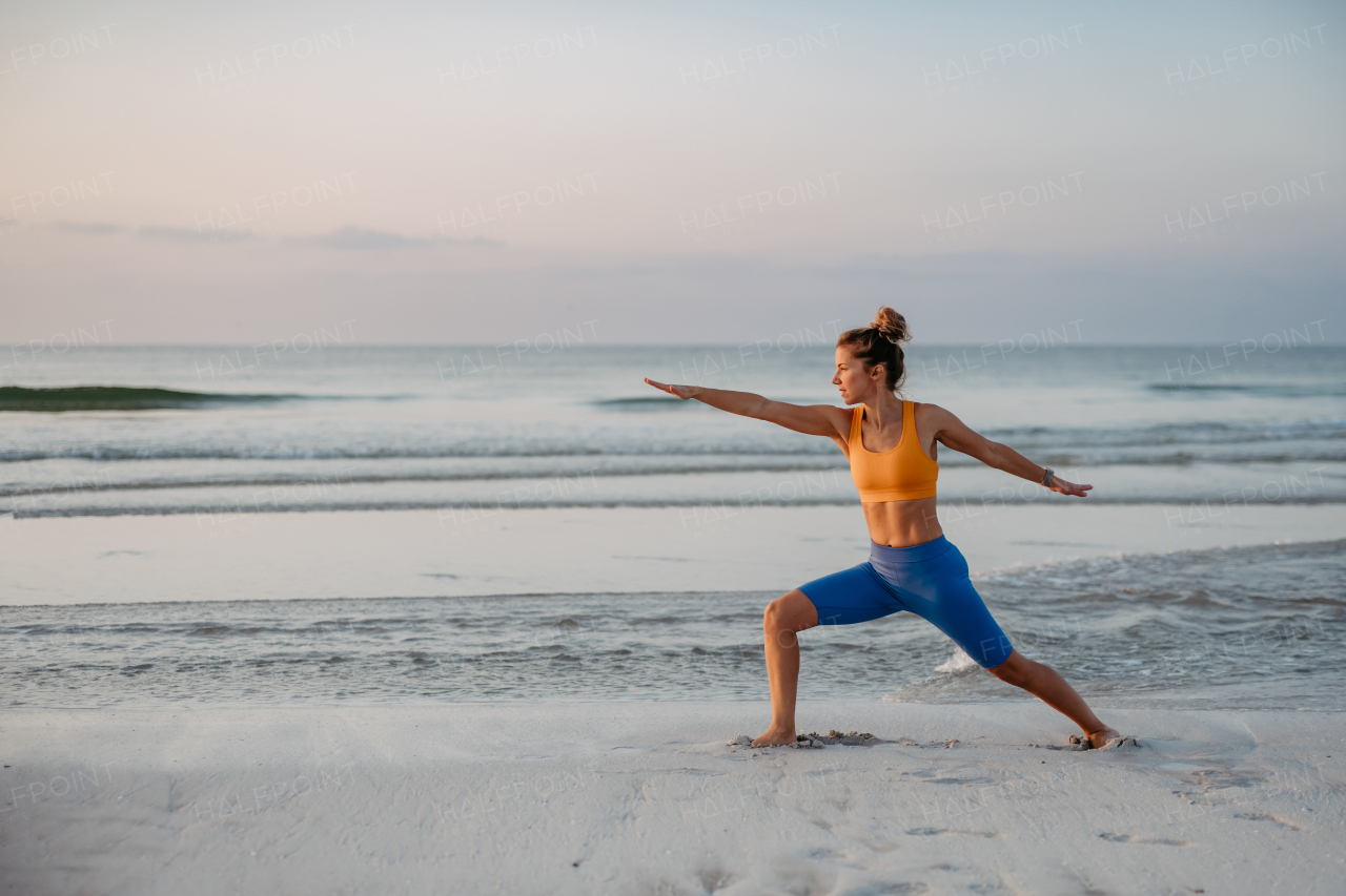 Young woman taking exercises at the beach, morning routine and healthy lifestyle concept.