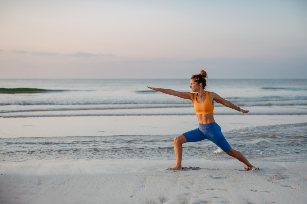 Young woman taking exercises at the beach, morning routine and healthy lifestyle concept.