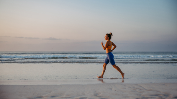 Young woman running at the beach, morning routine and healthy lifestyle concept.