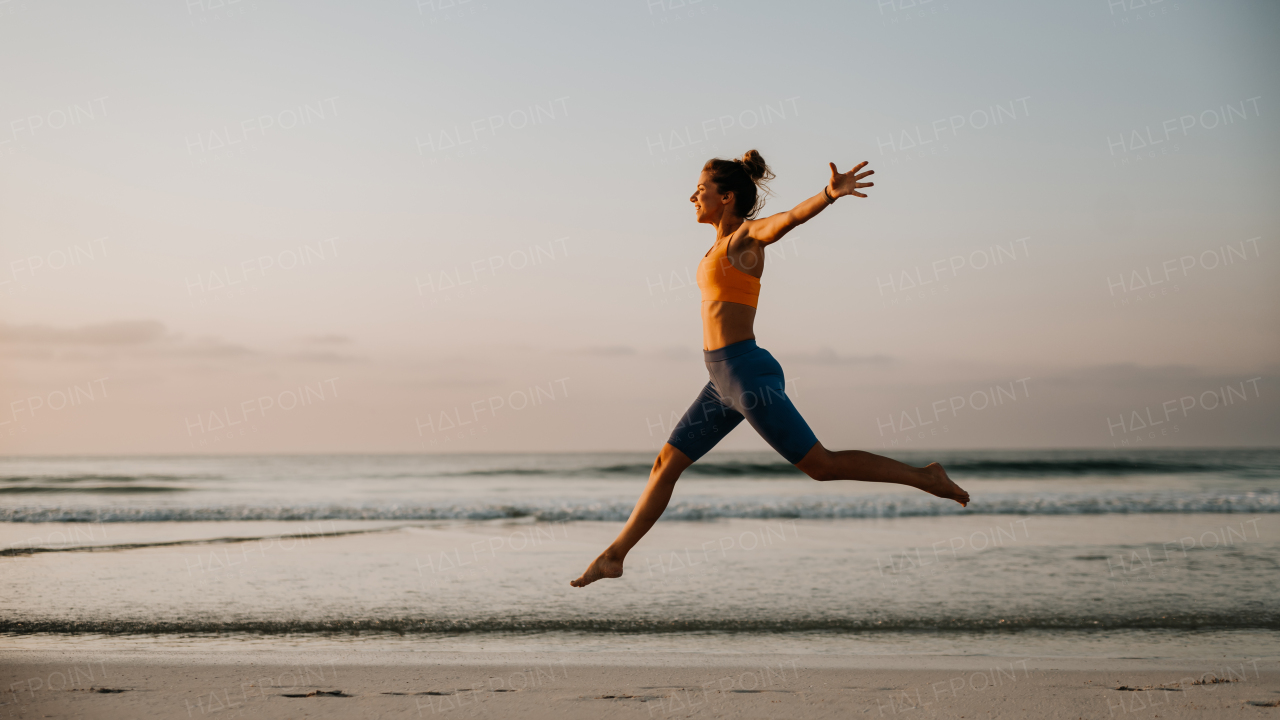 Young excited woman running and jumping at the beach, morning routine and healthy lifestyle concept.