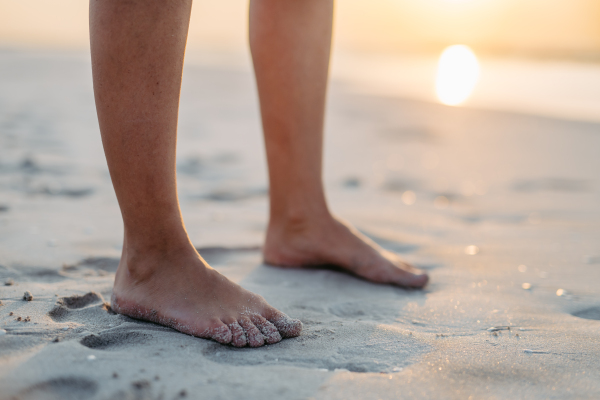 Close-up of womans feet in a sand, at sea.