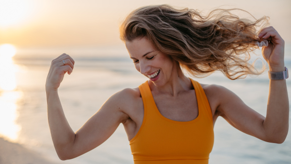 Young sportive woman showing her muscles at the beach.