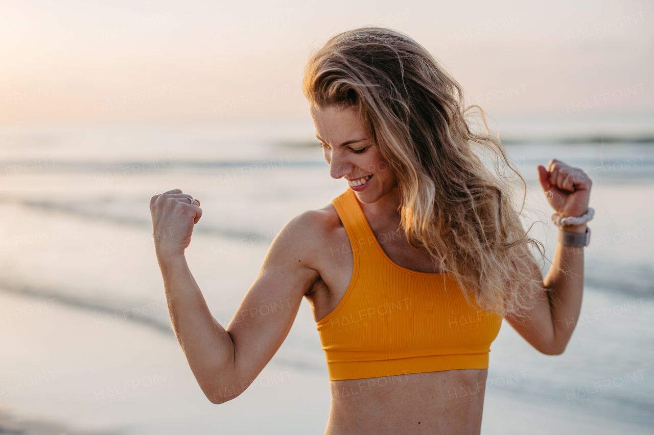 Young sportive woman showing her muscles at the beach.