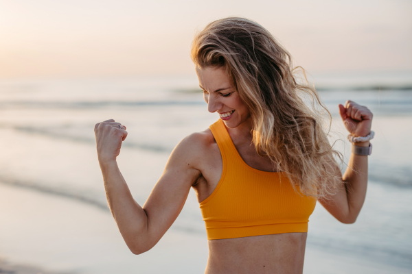 Young sportive woman showing her muscles at the beach.