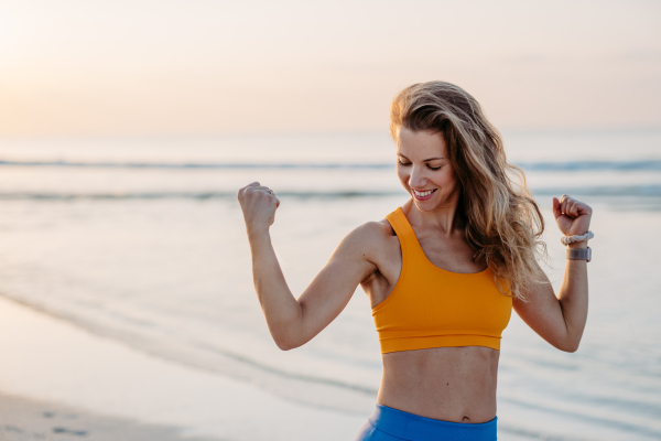 Young woman taking exercises at the beach, morning routine and healthy lifestyle concept.